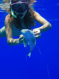 Woman snorkeling while holding fish in sea