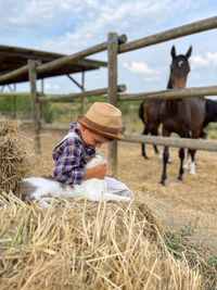 Cute boy with a cat in a horse landscape .rural