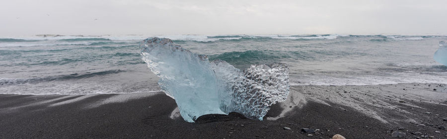 Waves splashing on shore against sky