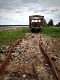 Abandoned railroad track on field against sky