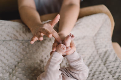 Mum making baby massage, mother massaging infant bare foot, preventive massage for newborn.