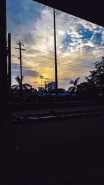 Silhouette city street against sky at sunset