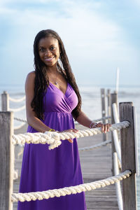 Portrait of a young woman standing against sea