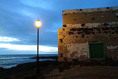 Illuminated street light against sky at night