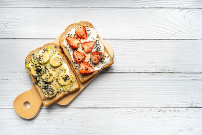 Healthy breakfast toasts with banana, sesame, strawberry, yoghurt on whole grain sandwich
