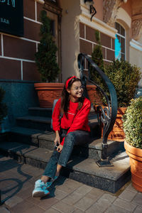 Portrait of smiling girl sitting on potted plant