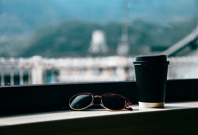 Close-up of sunglasses and coffee cup