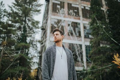 Portrait of young man standing against trees