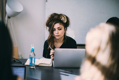 Young woman using phone while sitting on table