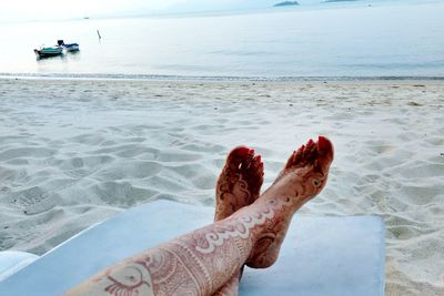 Low section of woman on beach against sky