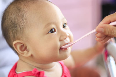 Cropped hand of woman feeding daughter with spoon at home