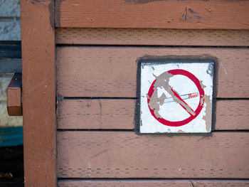 Close-up of sign on wood against wall