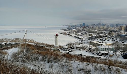 Snow covered road by buildings against sky