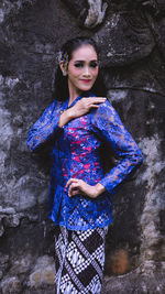 Portrait of smiling young woman standing against blue wall