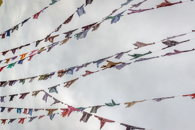 Low angle view of decorations hanging on branch against sky