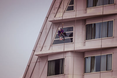 Low angle view of men hanging on window