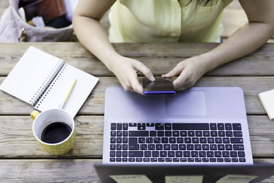 Midsection of man using mobile phone on table