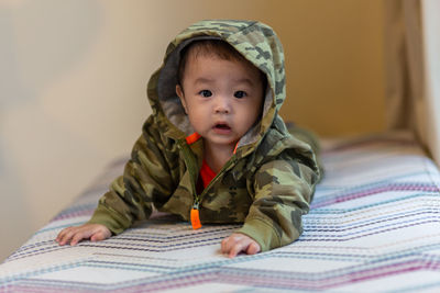 Portrait of cute baby girl lying on bed at home