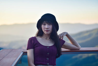 Portrait of woman sitting at observation point during sunset