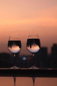 Close-up of wine glass on table against sky during sunset