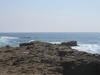 Scenic view of rocks on beach against clear sky