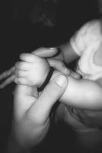 Midsection of woman holding baby hand