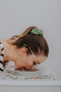 Close-up of woman wearing sunglasses with confetti against gray background