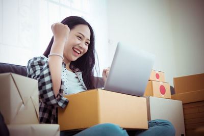 Young woman using phone while sitting on sofa at home