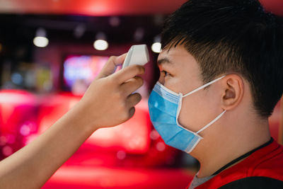 Cropped hand checking temperature of boy wearing flu mask