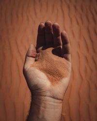 High angle view of human hand against sand