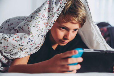 Close-up of boy playing on mobile phone 