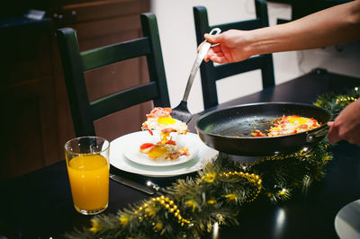 Midsection of woman serving food while standing by dining table at home