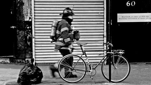 Blurred motion of fireman walking by cycle on sidewalk