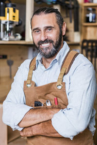 Portrait of smiling carpenter standing in workshop