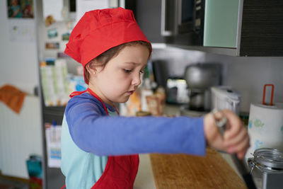 Girl in a red chef's hat is in the kitchen of her house