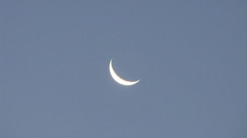 Low angle view of moon against blue sky