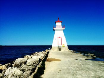 Lighthouse on beach against blue sky