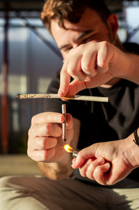 Midsection of man holding marijuana joint outdoors