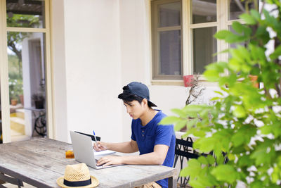 Man using laptop while studying at table in yard