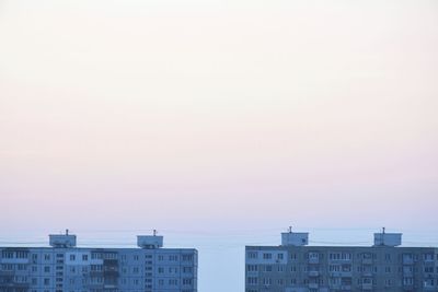 Exterior of buildings in city against sky at sunset