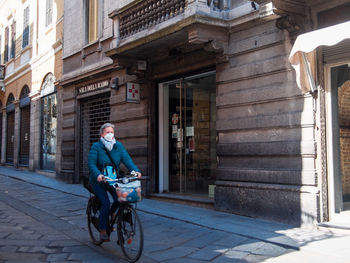 Full length of man riding bicycle on city street