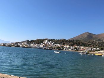Scenic view of sea by buildings against clear blue sky