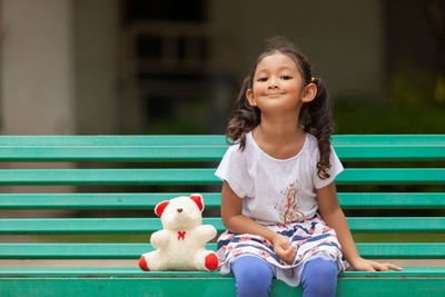 Portrait of a smiling girl sitting with toy