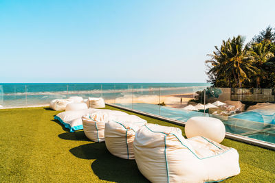 Lounge chairs by swimming pool at beach against clear sky