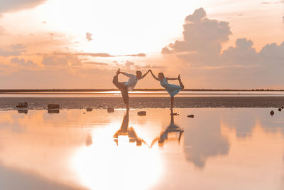 
man and woman doing yoga against the backdrop of the sunrise
