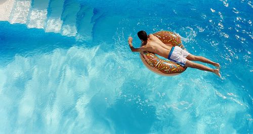 High angle view of man on donut inflatable ring in swimming pool