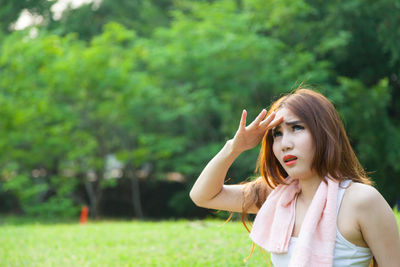 Woman shielding eyes while sitting on field