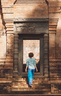 Full length rear view of woman standing against building