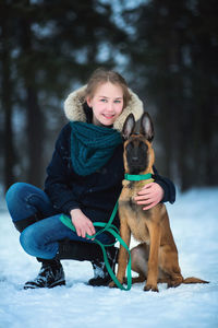Portrait of teenage girl with dog in snow
