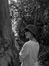 Side view of woman standing on tree trunk